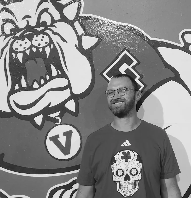 Aaron Husak smiling in front of a mural